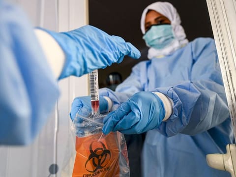 Laboratory workers bag a biological sample at a drive-through COVID-19 testing centre in Al Khawaneej, Dubai. 