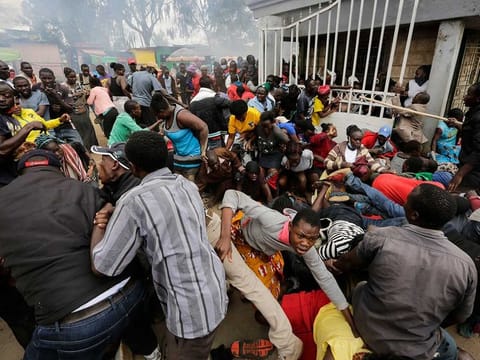 Residents desperate for a planned distribution of food for those suffering under Kenya's coronavirus-related movement restrictions push through a gate and create a stampede, causing police to fire tear gas and leaving several injured, at a district office in the Kibera slum, or informal settlement, of Nairobi, Kenya, on April 10, 2020. 