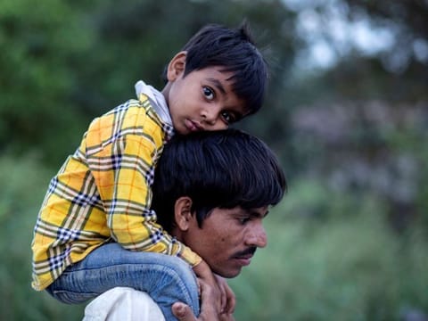 Dayaram Kushwaha, a migrant worker, carries his 5-year-old son, Shivam, on his shoulders as they walk along a road to return to their village, during a 21-day nationwide lockdown to limit the spreading of coronavirus, in New Delhi on March 26, 2020. 