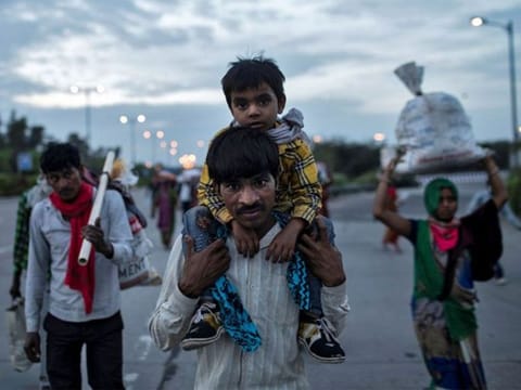 An Indian migrant worker carries his son as he walks along a road with others to return to their village, in New Delhi.