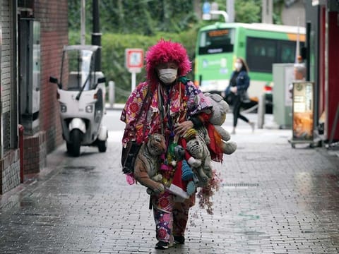 A man  wearing a mask and a colourful attire to help stop the spread of the new coronavirus walks in the Shinjuku Ward in Tokyo 