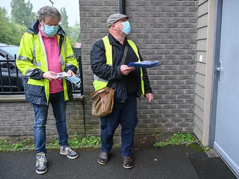 Dunkirk municipal employees wearing face masks stand in front of a house during a distribution of cloth face masks to residents, in anticipation of the end of the lockdown on May 10, in Dunkirk, northern France on April 28, 2020, on the 43rd day of a lockdown in France aimed at curbing the spread of the COVID-19 disease, caused by the novel coronavirus. 