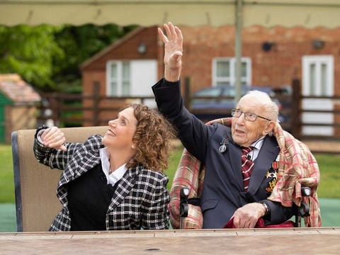 Second World War veteran Captain Tom Moore with his daughter Hannah, as they react to Battle of Britain Memorial Flight flypast of a Spitfire and a Hurricane passing over his home as he celebrates his 100th birthday, in Marston Moretaine, Britain, Thursday April 30, 2020. 