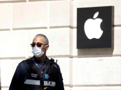 A policeman wearing a protective face mask walks past an Apple store 