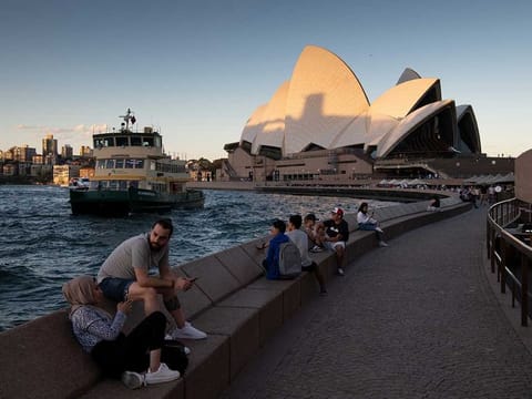 People sit along the harbour in Sydney, March 20, 2020. New Zealand and Australia could soon open their borders to each other, creating what they call a “Trans-Tasman bubble”. 