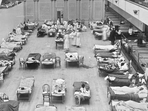 In this 1918 file photo made available by the Library of Congress, volunteer nurses from the American Red Cross tend to influenza patients in the Oakland Municipal Auditorium, used as a temporary hospital.  
