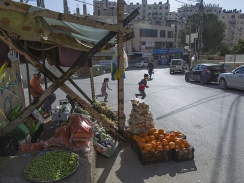 In this Tuesday, April 28, 2020 photo, a Palestinian vendor displays his vegetables in the street as the main vegetable market remains closed, part of lockdown and quarantine measures to protect residents from the coronavirus, in the West Bank village of Kufr Aqab. As the coronavirus pandemic gathered strength in April, community leaders in Kufr Aqab, a Palestinian neighbourhood on the outskirts of occupied Jerusalem, tried to impose lockdown and quarantine measures to protect residents. 
