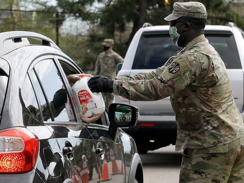 A Massachusetts US Army National Guard soldier hands a gallon container of milk to a recipient in a vehicle at an event sponsored in part by Dairy Farmers of America, at Boston College High School, Thursday, May 7, 2020, in Boston. Dairy farmers have a milk surplus because demand has dropped as schools and restaurants are closed during the corona virus pandemic, and some farmers have had to pour excess milk away.