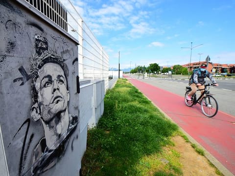A man wearing a protective face mask cycles past a mural of Juventus' Cristiano Ronaldo outside of Juventus' Allianz Stadium.