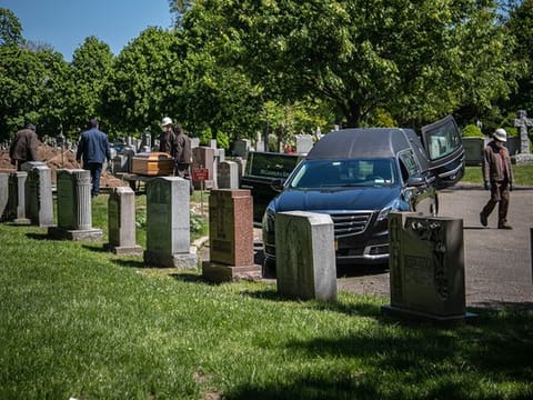 Cemetery workers prepare to bury a casket from McLaughlin & Sons funeral home, without any family present because of coronavirus restrictions, Wednesday May 13, 2020, at Holy Cross Cemetery in the Brooklyn borough of New York. 