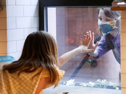 Lydia Hassebroek says hi to her friend Rose through her kitchen window during the outbreak of the coronavirus disease (COVID-19) in Brooklyn, New York, U.S., May 17, 2020. 