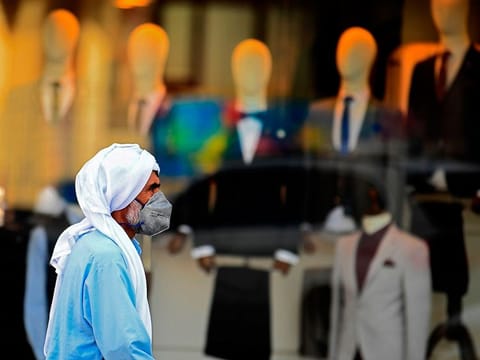 A man wearing a protective mask walks past a clothing shop in Dubai. 