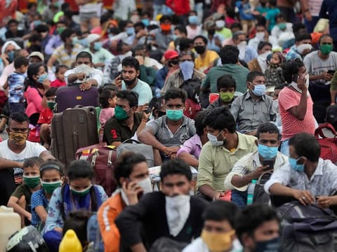 Migrant workers from other states wait outside a railway station to catch a train to return to their homes, in Mumbai, India, Friday, May 15, 2020. 