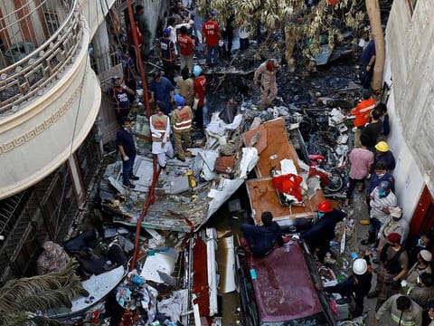 Rescue workers gather at the site of a passenger plane crash in a residential area near an airport in Karachi, Pakistan, May 22, 2020. 