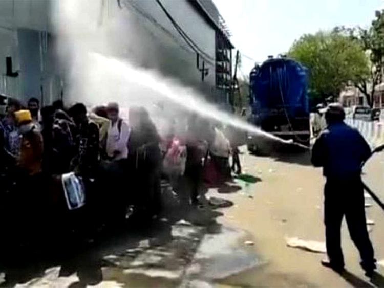 Migrants waiting for medical screening sprayed with disinfectant in New Delhi