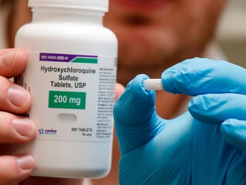 A pharmacist holds a bottle and a pill of Hydroxychloroquine at Rock Canyon Pharmacy in Provo, Utah. 