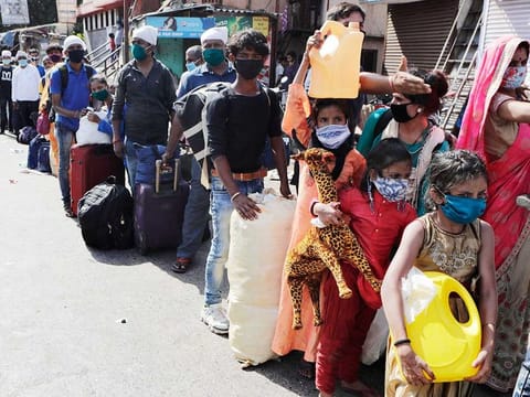 Migrant workers and their families gather for transport to the railway station for their onward journey to their home states, at Dharavi in Mumbai, India, Tuesday, May 26, 2020. 