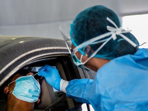 A paramedic staff collects swab samples at a coronavirus drive-through screening center located at Sharjah Golf and Shooters Club. 
