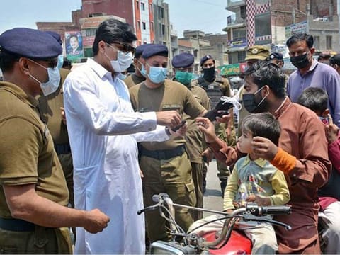 Muhammad Ali, Deputy Commissioner in Faisalabad, distributing face masks among the people as part of the coronavirus awareness campaign. 