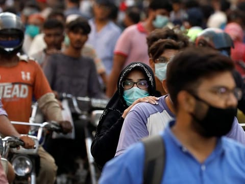 A woman rides on a motor bike as she wears a protective face mask in Karachi, Pakistan