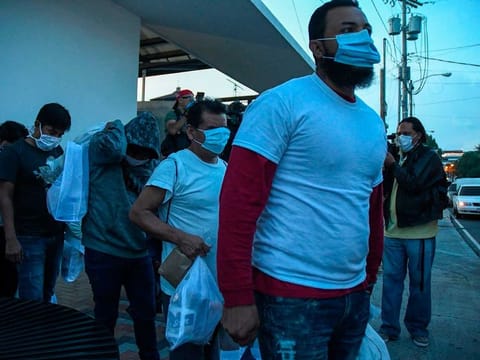 Migrants, part of a group of 50 Guatemalans deported from the United States, wear face masks as a preventive measure against the novel coronavirus COVID-19, as they get into a bus upon landing at the Air Force base in Guatemala City on June 9, 2020. 