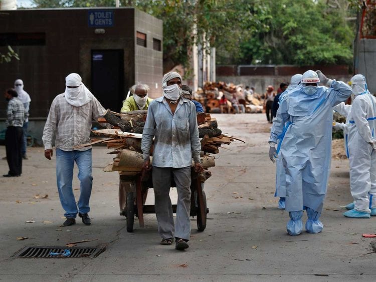Workers push a handcart carrying wood for the funeral pyre of victims of COVID-19 Delhi