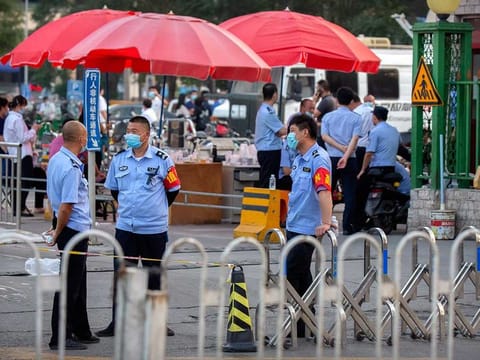 Chinese police stand outside the entrance to a building holding a beef and lamb market in Beijing that was closed by authorities after it was visited by a person who tested positive for COVID-19, Friday, June 12, 2020. 