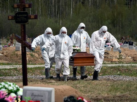 Gravediggers in protective suits carry the coffin of a COVID-19 victim as relatives and friends stand at a distance in the section of a cemetery reserved for coronavirus victims in Kolpino, outside St. Petersburg, Russia.  A WHO report has found crucial flaws in the global response in early 2020 to the COVID-19 outbreak.