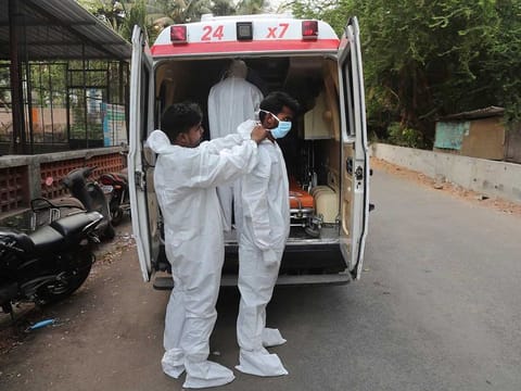 Izhaar Hussain Shaikh, right, an ambulance driver who works for HelpNow, an initiative to help the stretched services of first responders, is assisted in wearing the face mask before picking up a COVID-19 patient in Mumbai, India May 28, 2020.