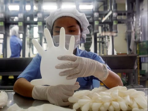 A worker carries out a test on a glove at a factory in Meru outside Kuala Lumpur. 