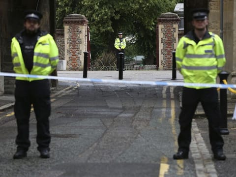 Police stand guard at the Abbey gateway of Forbury Gardens park in Reading town centre following Saturday's stabbing attack in the gardens, Sunday June 21, 2020. Thames Valley Police said a 25-year-old man from the town has been arrested and they are not looking for anyone else.  (Jonathan Brady/PA via AP)