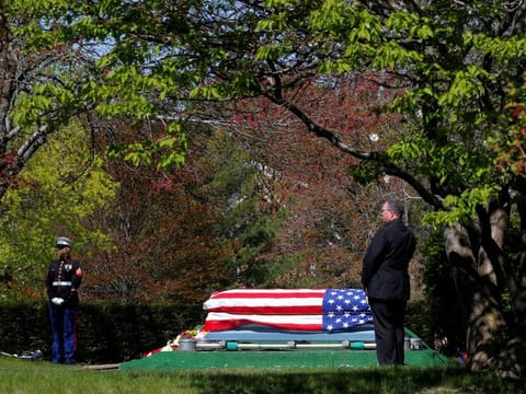 A US Marine stands beside the flag-draped coffin of a veteran who contracted COVID-19, at the Woodlawn Cemetery in Everett, Massachusetts