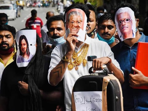 Youth Congress activists hold pictures of Kerala Chief Minister Pinarayi Vijayan (C), former UAE consulate officer Swapna Suresh (L), and State IT Secretary M Sivasankar (R) during a protest over the Kerala gold smuggling case, in Kochi, Tuesday, July 7, 2020. 