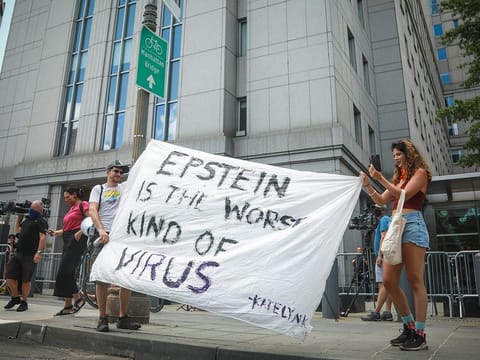 Multimedia artist Katelyn Kopenhaver, right, with help from her brother Brent Kopenhaver, unfurls a banner reading "[Jefferey] Epstein is the worst kind of virus," outside federal court where a judge held a bail hearing by video for Epstein's former girlfriend Ghislaine Maxwell, Tuesday, July 14, 2020, in New York.