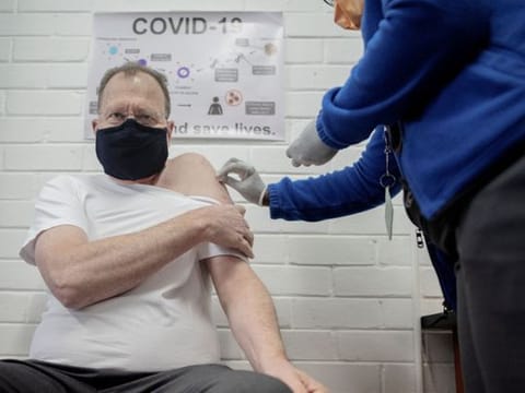Professor Martin Veller (L), the Dean of the Faculty of Health Sciences at the University of the Witwatersrand (Wits University), receives  an experimental vaccine for COVID-19 coronavirus at the Respiratory & Meningeal Pathogens Research Unit (RMPRU) at Chris Hani Baragwanath Hospital in Soweto on July 14, 2020. - Six senior clinicians in the Faculty of Health Sciences at Wits University have volunteered to participate in South Africas first COVID-19 vaccine trial. (Photo by Luca Sola / AFP)