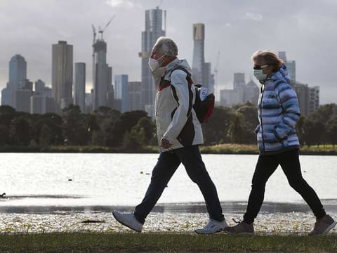People walk along Albert Park lake in Melbourne on July 13, 2020, as five million people in Australia's second-biggest city began a new lockdown following a resurgence of coronavirus cases.
