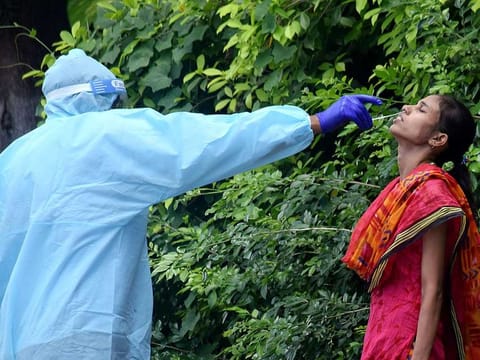 A health worker wearing PPE kit collects the swab sample of a woman for COVID-19 test at a collection centre, during the lockdown, in Patna on Thursday, July 16, 2020. 