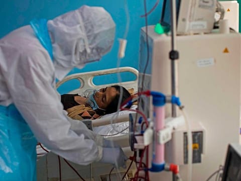 In this photograph taken on July 15, 2020 a doctor wearing Personal Protective Equipment (PPE) suit works next to a COVID-19 coronavirus patient at the Intensive Care Unit of the Sharda Hospital, in Greater Noida. 