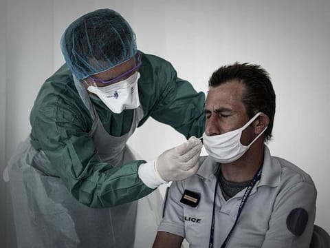 A medical personnel takes a nasal swab from a police officer at a COVID-19 (novel coronavirus) free screening booth set up in the arrival hall of the Bordeaux-Merignac international airport in Merignac, southwestern France, on July 23, 2020. 