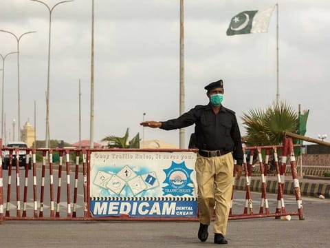 A policeman wearing a protective mask directs traffic away from the closed road to Clifton beach in Karachi, Pakistan, on Tuesday, July 28, 2020. Pakistan is at risk for a second wave of virus infections during the upcoming Eid holidays as millions travel to their home towns and mingle at family and religious gatherings. 