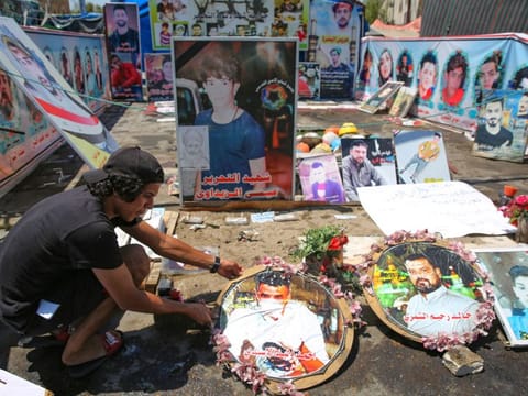 An Iraqi anti-government demonstrator arranges portraits of killed protesters in Tahrir Square in the capital Baghdad, on August 1, 2020. 