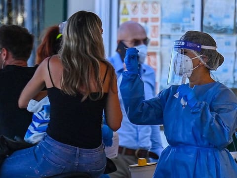 A holidaymaker on a motorbike (L) returning from Sardinia by ferry undergoes a compulsory drive-through swab test on August 23, 2020 at the port of Civitavecchia, northwest of Rome, during the COVID-19 infection, caused by the novel coronavirus. Italy has recorded 1,071 new cases of coronavirus in the last 24 hours, breaking the symbolic barrier of 1,000 cases per day for the first time since May 12, according to an official report published on August 22, 2020. 
