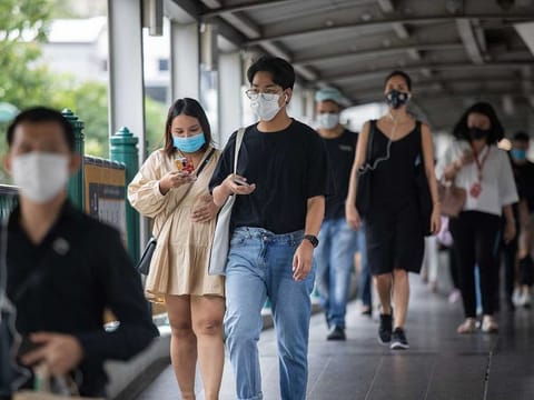 Commuters wearing protective masks walk along a pedestrian bridge in Bangkok, Thailand. 