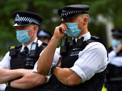 Police officers wearing face masks stand guard as climate activists protest outside the Shell building in London, Britain, September 8, 2020. 
