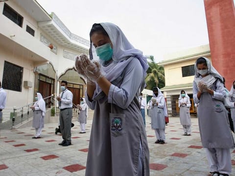 Students wearing face masks to prevent the spread of coronavirus, pray prior to going their classrooms at a school, in Karachi, Pakistan (File)