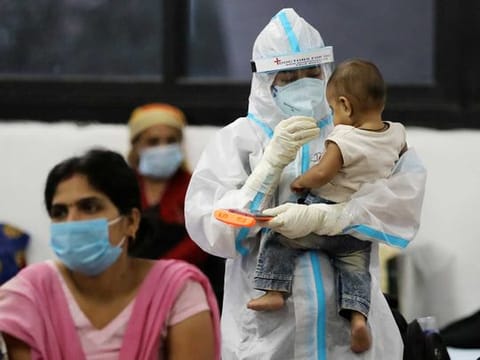 A medical worker in personal protective equipment (PPE) plays with a child of a woman recovering inside a quarantine centre for the coronavirus disease (COVID-19) patients amidst the spread of the disease at an indoor sports complex in New Delhi
