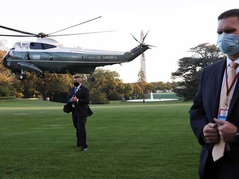 US Secret Service agents stand at their posts on the South Lawn of the White House in Washington as the Marine One helicopter with US President Donald Trump onboard lifts off to depart the White House and fly to Walter Reed National Military Medical Center.