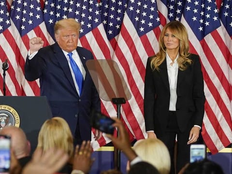 US President Donald Trump gestures after speaking during an election night party with U.S. First Lady Melania Trump, right, in the East Room of the White House in Washington, D.C., U.S., on Wednesday, Nov. 4, 2020. Trump declared he had won re-election against Joe Biden and said he would ask the Supreme Court to intervene, even as several battleground states continue to count votes. 