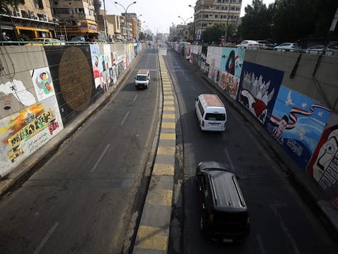 Cars drive out of a tunnel in front of walls covered with murals painted by  an anti-government protesters near Tahrir Square in the centre of Iraq's capital Baghdad on November 8, 2020. 