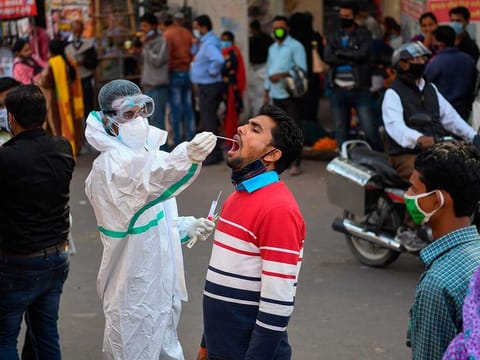 A medical worker collects a swab sample from a man for a RT-PCR test for the COVID-19 coronavirus along a street in New Delhi on November 17, 2020. 